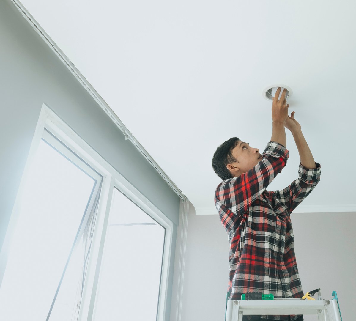 Handyman Installing a Light Bulb on the Ceiling